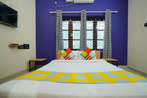 a bedroom with a large bed and a purple wall at Hotel O Majestic Stays in Kazhakuttam