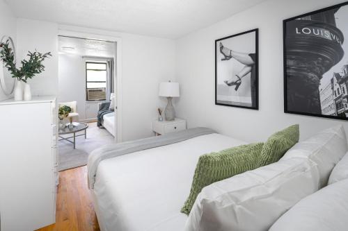 a white bedroom with a bed and a living room at Bright 1BR Escape in Lower East Side NYC in New York