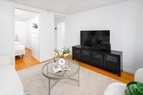 a living room with a glass table and a flat screen tv at Bright 1BR Escape in Lower East Side NYC in New York