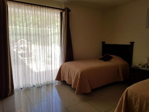 a bedroom with a bed and a large window at Comfort Hostel in Guatemala