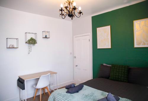 a bedroom with a green wall with a bed and a desk at The Eastbourne Suite, FREE CAR PARK in Eastbourne
