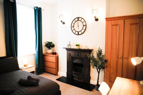 a living room with a clock on the wall and a bed at The Eastbourne Suite, FREE CAR PARK in Eastbourne