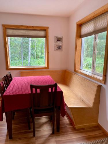 a dining room with a table and two windows at Talkeetna Wilderness Lodge & Cabin Rentals in Sunshine