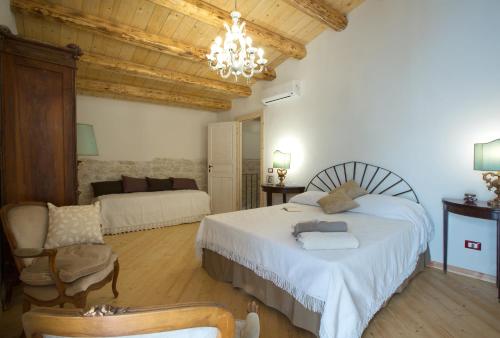 a bedroom with a bed and a couch and a chandelier at Villa Barone Alfieri in Pozzallo