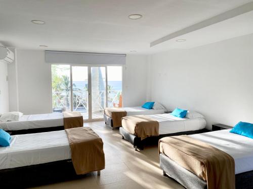 Zimmer mit 4 Betten und einem großen Fenster in der Unterkunft Hostal San Andres Divers in Gustavo Rojas Pinilla International