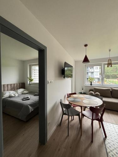 a living room with a bed and a table and a bedroom at Dębina Spot 27 in Debina