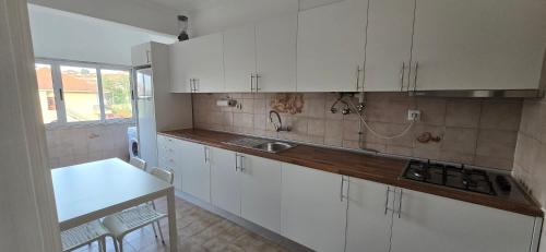 a kitchen with white cabinets and a sink at Casa da Vista Rio in Amora
