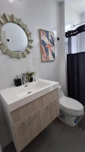 a bathroom with a sink and a toilet and a mirror at PH Las Islas Punta Barco Viejo a 3 min de Coronado in San José