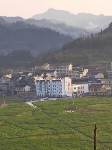 a group of buildings in a field with mountains in the background at 笑涡SmileNest Downtown Luxury Suite for 2-10 Guests, Zhangjiajie Attraction Ticket Service, Ideal for Couples, Families & Groups in Zhangjiajie