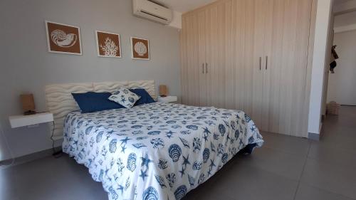 a bedroom with a bed with a blue and white comforter at PH Las Islas Punta Barco Viejo a 3 min de Coronado in San José