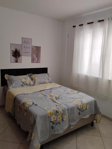 a bedroom with a bed with a blue comforter and yellow flowers at AP térreo-Rio das Ostras próx Enseada -Costazul in Rio das Ostras