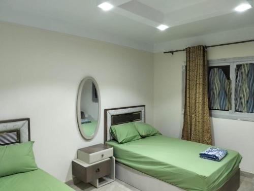 - une chambre avec 2 lits verts et un miroir dans l'établissement شقق الفندقية ميامي امام بئر مسعود, à Alexandrie