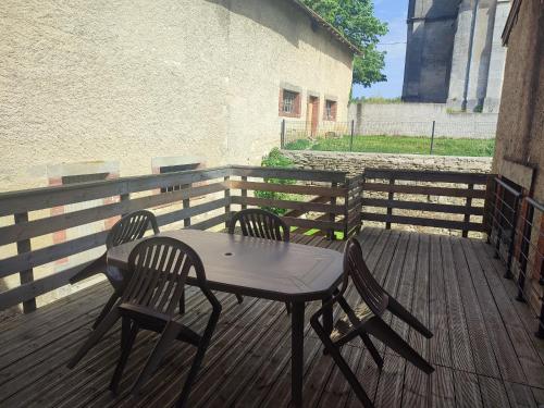 a table and chairs on a wooden deck at Gîte confortable avec cheminée et parking, proche Verdun - FR-1-585-159 in Dompcevrin
