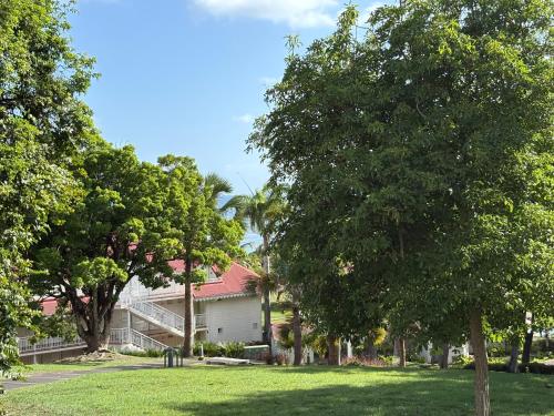 a house with trees in front of a yard at TI KAZ DOUDOU - village de vacances bord de mer in Sainte-Anne