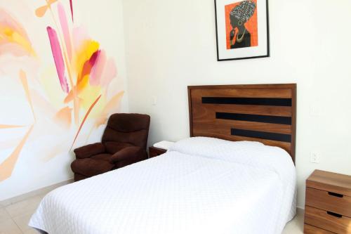 a bedroom with a bed and a chair at La Casa del Mural in Mixquiahuala
