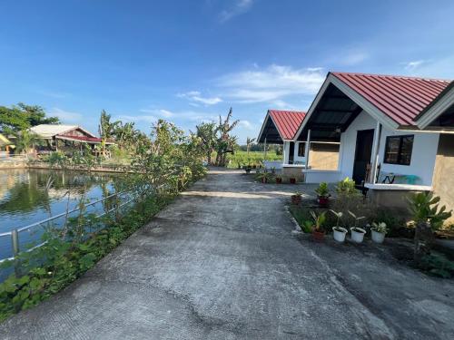 a house with a pathway next to a body of water at Jazz Ferme Inn Batuan Bohol in Batuan