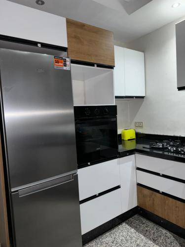 a kitchen with white cabinets and a stainless steel refrigerator at Bel appartement à ifrane in Ifrane