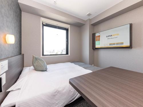 a small room with a bed and a tv at Super Hotel Premier Toyama Castle Park in Toyama