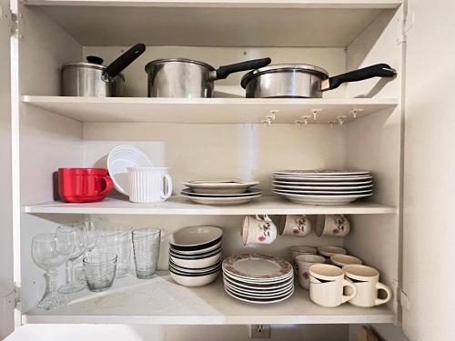 a cupboard filled with dishes and pots and pans at 3 Bedroom Apartment - 5 Beds in Abbotsford