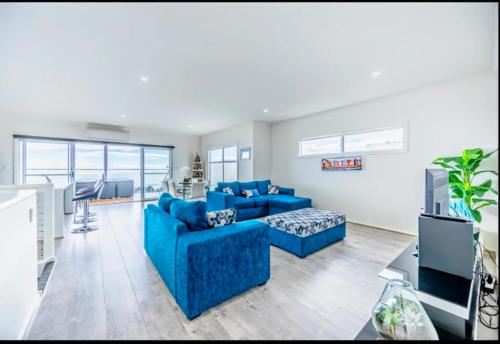 a living room with blue couches and a tv at Ocean Front retreat Fleurieu Coast Wirrina Cove in Wirrina Cove