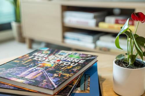 a book on a table next to a potted plant at 108 Flinders - Stunning Views & Prime Location in Melbourne