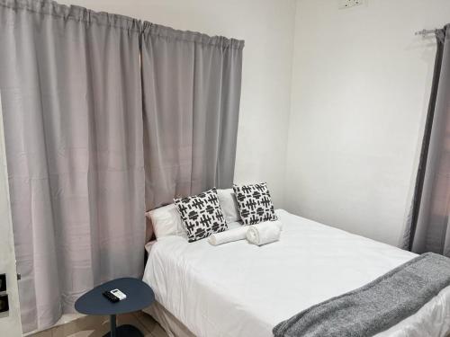 a bedroom with a bed with white sheets and pillows at Marble inn accommodation in Durban