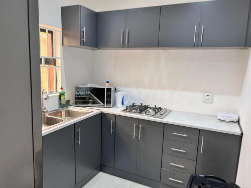 a kitchen with gray cabinets and a sink and a microwave at Marble inn accommodation in Durban