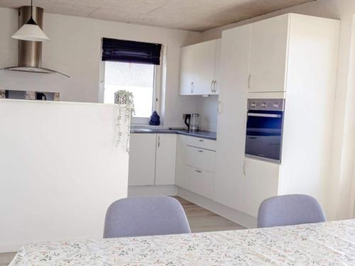 a kitchen with white cabinets and a table and chairs at 6 person holiday home in Vestervig in Vestervig