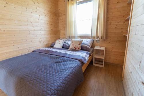 ein Schlafzimmer mit einem Bett in einem Holzzimmer in der Unterkunft Comfortable holiday cottages in Mielno in Mielno