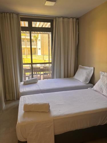 two beds in a room with a window at Encanto Moanara in Luis Correia