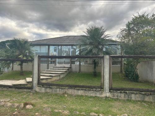 a fence in front of a building with palm trees at Recanto do sossego!! in Morretes