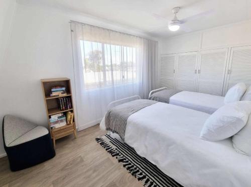 a bedroom with two beds and a window at Central Bargara Beach Bungalow by UG in Bargara