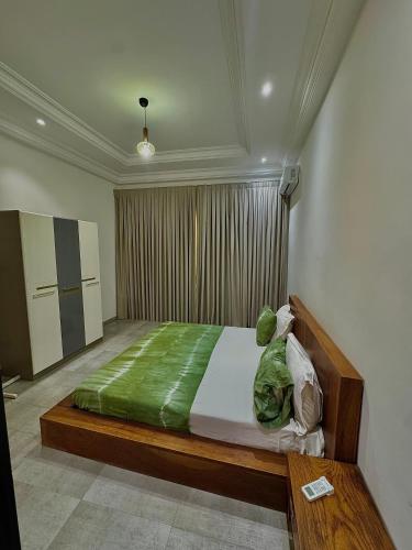 a bedroom with a bed with a green blanket at Maisons d'Hotes Les jardins de keur fary 