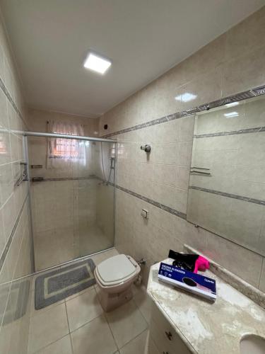 a bathroom with a toilet and a glass shower at Casa Confortável 03 Quartos Com Suite, Churrasqueira, Banheira e Garagem in Curitiba