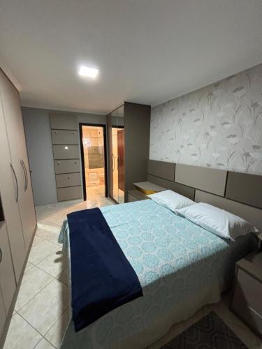 a bedroom with a large bed with a blue blanket at Casa Confortável 03 Quartos Com Suite, Churrasqueira, Banheira e Garagem in Curitiba