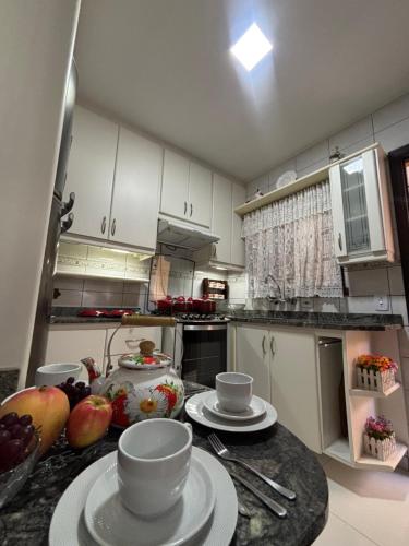 a kitchen with a table with plates and bowls on it at Casa Confortável 03 Quartos Com Suite, Churrasqueira, Banheira e Garagem in Curitiba