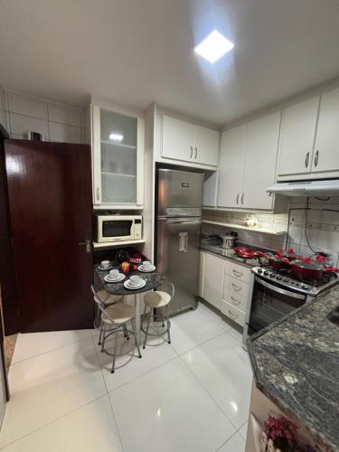 a kitchen with white cabinets and a table and chairs at Casa Confortável 03 Quartos Com Suite, Churrasqueira, Banheira e Garagem in Curitiba
