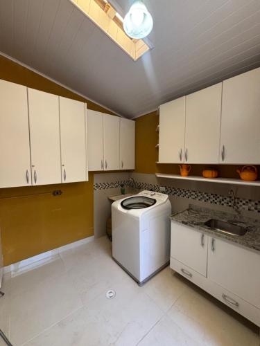 a kitchen with a washing machine in the middle at Casa Confortável 03 Quartos Com Suite, Churrasqueira, Banheira e Garagem in Curitiba