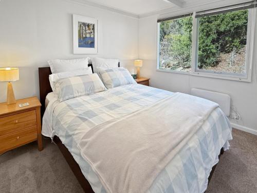 a bedroom with a large bed and two windows at River Flat in Merrijig