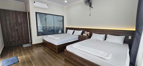 a bedroom with two beds and a large window at Homestay Dat Viet in Tân Phú