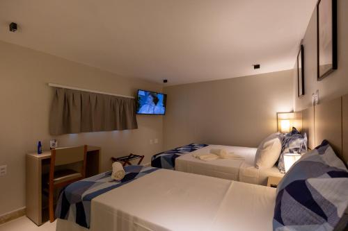 a hotel room with two beds and a tv at Aira Hotel in Sobral