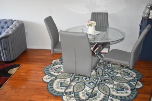 a dining room with a glass table and chairs at 3BR & 2Bath Bronx Stay-Private Suite-Parking in Bronx