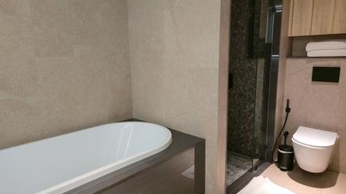 a bathroom with a bath tub and a toilet at La Green Hotel and Residence in Bang Tao Beach