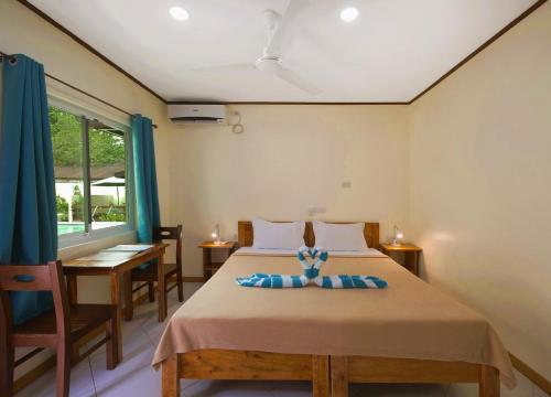 a bedroom with a bed and a table and a window at Alona Austria Resort in Panglao
