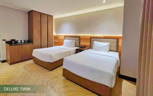 a hotel room with two beds and a table at Acacia Hotel Bacolod in Bacolod