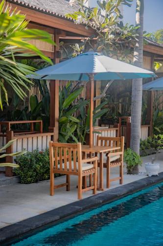 two chairs and an umbrella next to a swimming pool at Villa Tahid in Gili Air
