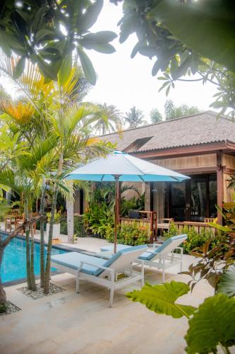 a pool with two lounge chairs and an umbrella at Villa Tahid in Gili Air