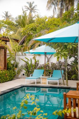 a swimming pool with two chairs and umbrellas at Villa Tahid in Gili Air
