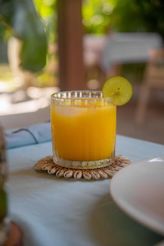a glass of orange juice with a lime on a table at Villa Tahid in Gili Air