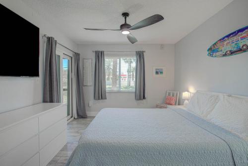 a white bedroom with a bed and a ceiling fan at Ocean Side Complex with Heated Pool B-15 in Saint Augustine